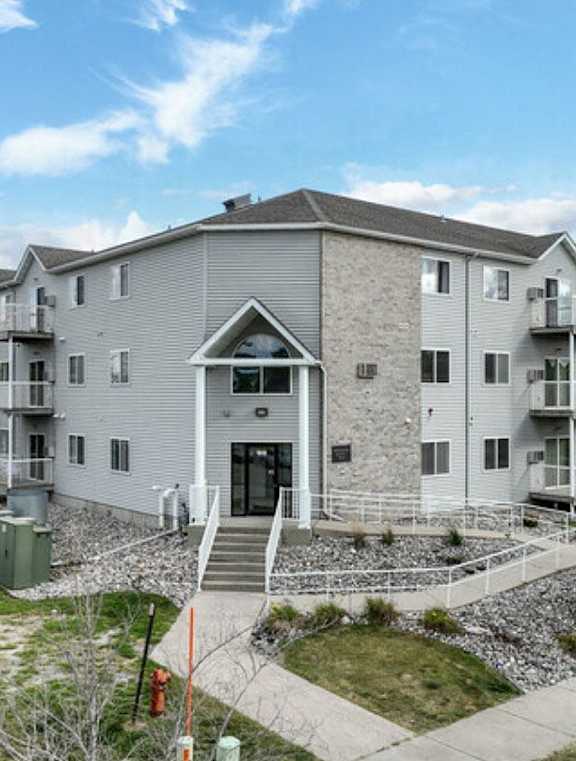 an apartment building with stairs and a sidewalk in front