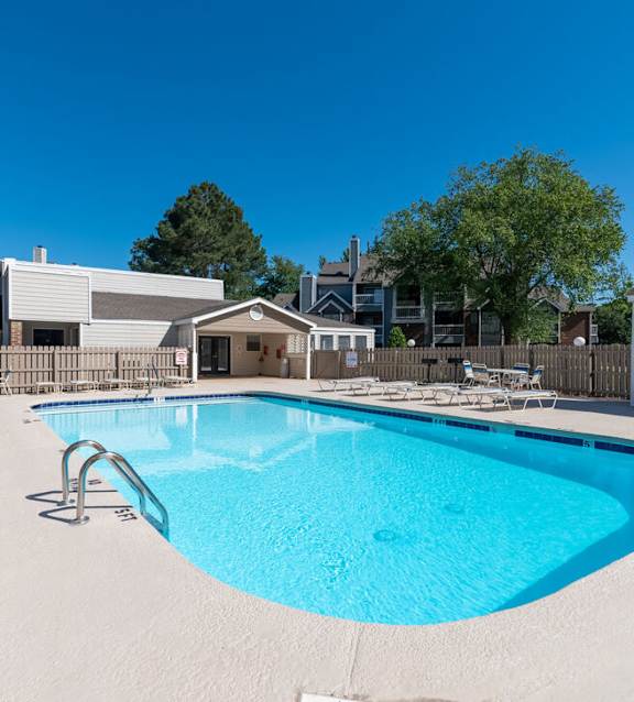 A swimming pool with sun loungers and a building in the background.