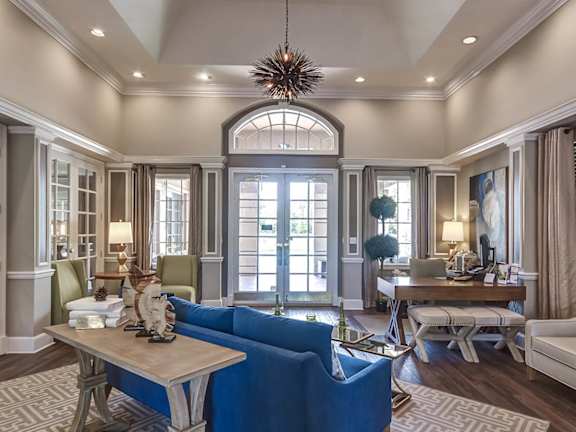 A large, well-lit living room with a blue sofa and wooden floors at Heritage Cove Apartments in Stuart, FL, 34997