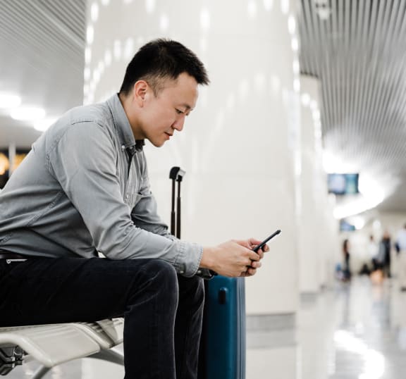 a man sitting in a chair looking at his phone in the airport