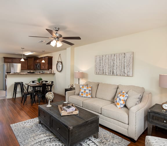 A living room with a couch, coffee table, and a ceiling fan.