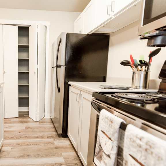a kitchen with white cabinets and a stove and a refrigerator