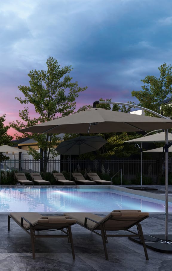 a swimming pool with chairs and umbrellas at dusk