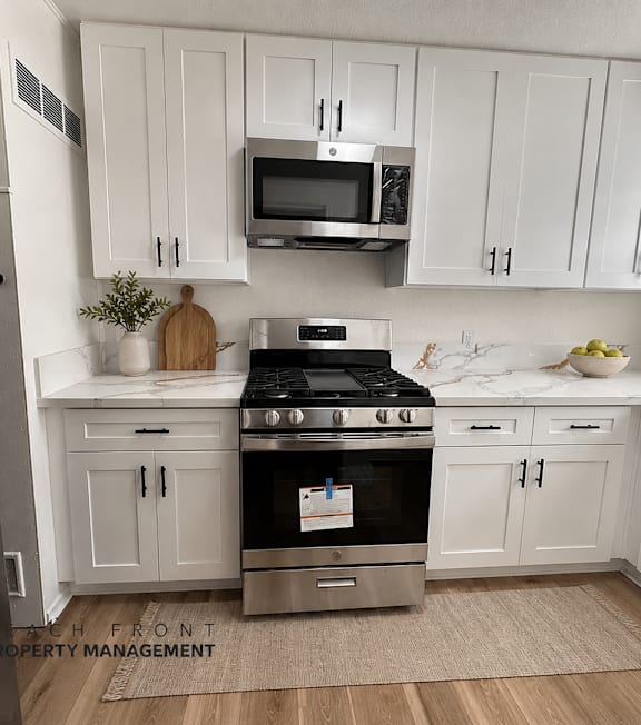 A kitchen with white cabinets and a stainless steel refrigerator.