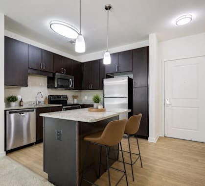 A kitchen with a white island and black cabinets.