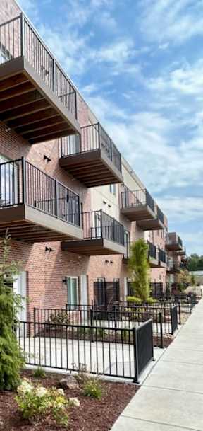 A red brick building with balconies and a black fence.