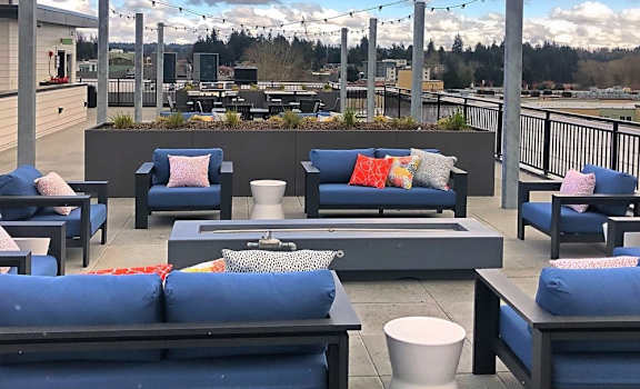 a rooftop lounge with blue couches and pillows on a roof