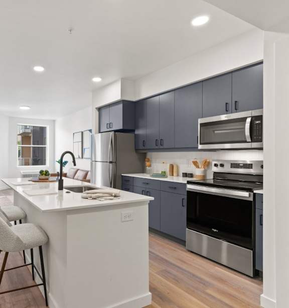 A modern kitchen with a white island and stainless steel appliances.