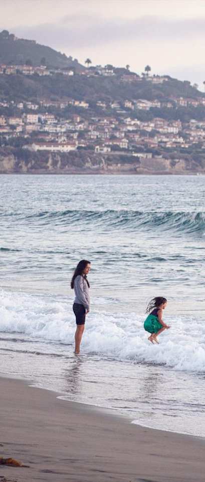 A woman and a child are playing in the waves at the beach.