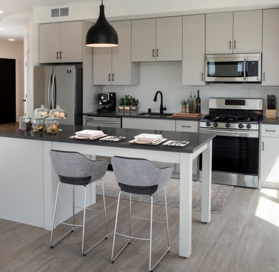 a kitchen with white cabinets and a large island with two stools