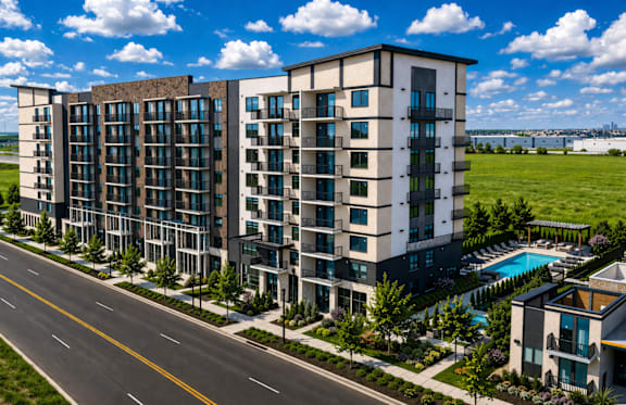 A modern apartment building with a pool and a road in front.