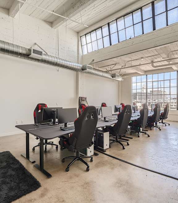 A room with a long table and chairs with a laptop on it.