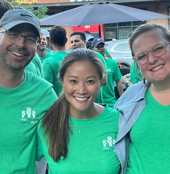 A group of people wearing green shirts are posing for a photo.