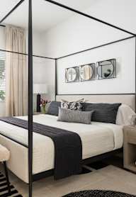 A modern bedroom with a four poster bed and a large mirror on the wall.