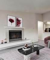 A living room with a fireplace and a painting of red flowers on the wall.