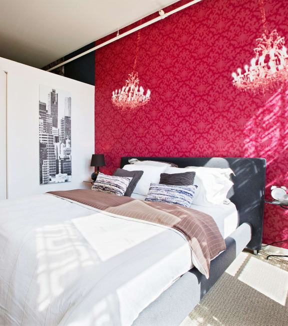a bedroom with a red wall and a white bed