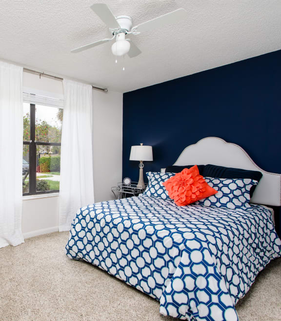 a blue and white bedroom with a bed and a window at Boca Colony Apartments, Florida