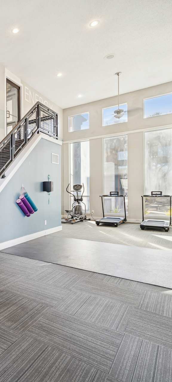 A gym with a staircase and a weight machine.