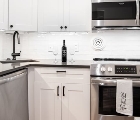a white kitchen with stainless steel appliances and white cabinets