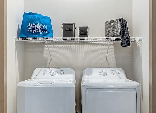 Two white washing machines in a small laundry room.