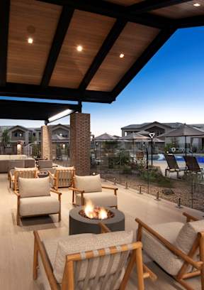 A patio with a fire pit and chairs.