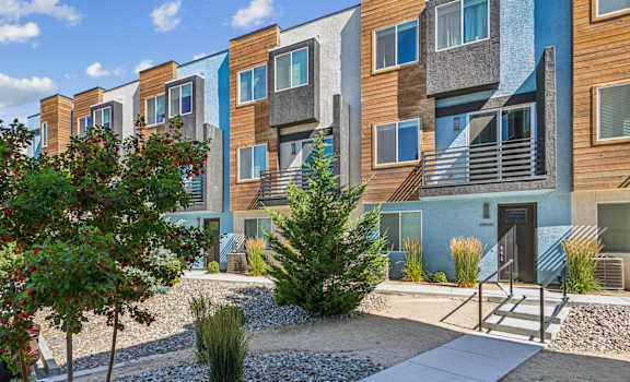 an exterior view of an apartment building with trees and a sidewalk