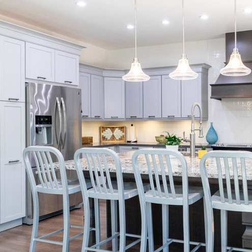A kitchen with white cabinets and a table with chairs.