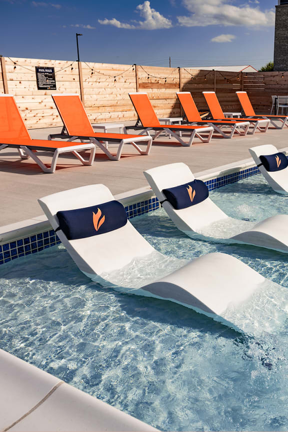 a group of lounge chairs on the side of a pool