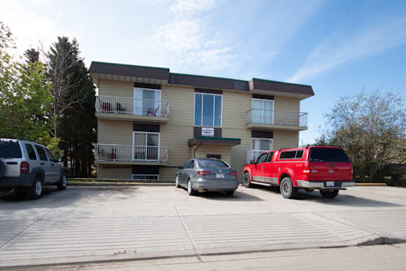A red truck is parked in front of a two-story apartment building.