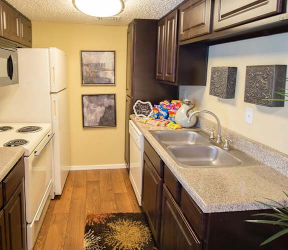 a kitchen with a white stove top oven next to a sink and a refrigerator