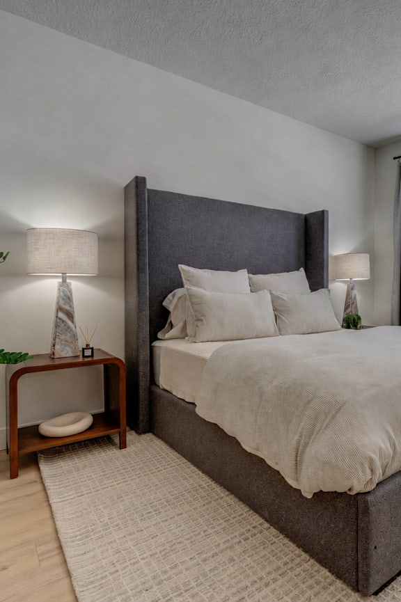 A bedroom with a large bed and a potted plant.