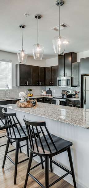 A kitchen with a white island and black chairs.