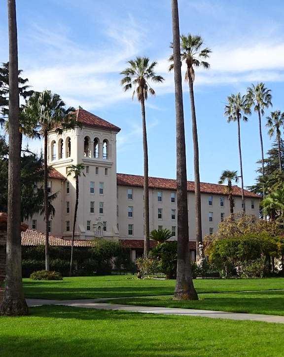 A building with a tower and palm trees in front of it.