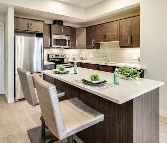 A modern kitchen with a stainless steel refrigerator and wooden flooring.