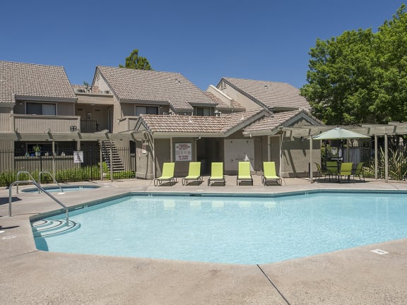 Zinfandel Village apartments pool and spa area with lounge chairs, a table and sun umbrella 