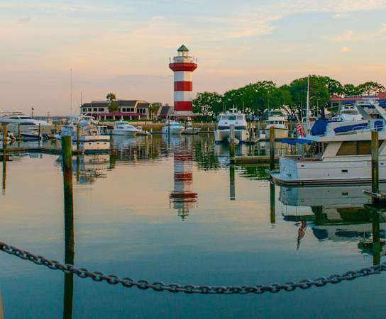 a boat docked at a marina with a lighthouse in the background at The Standard, Charleston, SC, 29412
