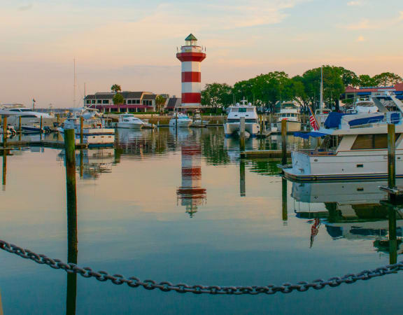 a boat docked at a marina with a lighthouse in the background