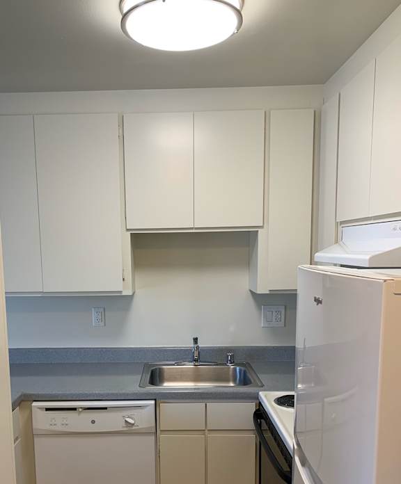 a small kitchen with a white counter top and a refrigerator