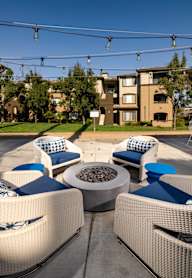 A patio with white wicker chairs and blue cushions.