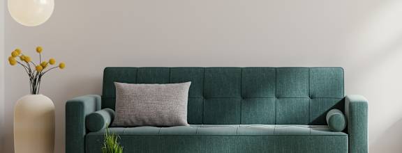 A living room with a green couch, a small table, and a potted plant.