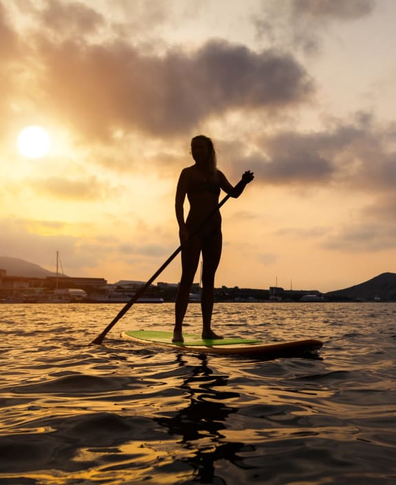 Woman Paddleboarder In Silhouette at Sunset