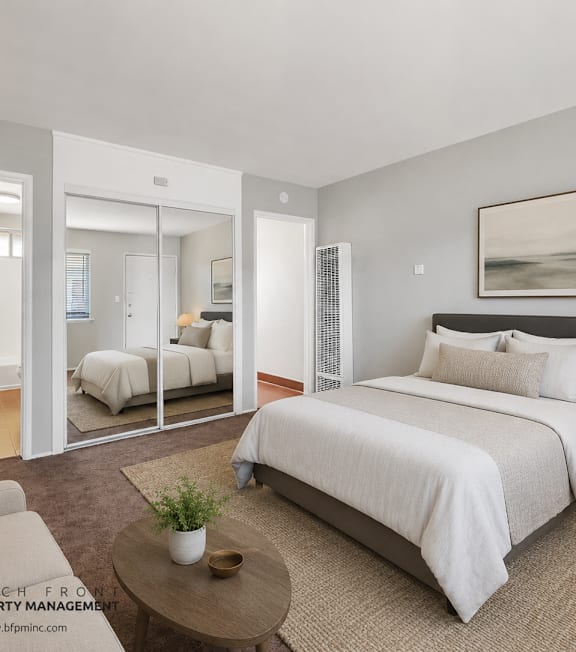 A well-lit bedroom with a large bed and a painting on the wall.