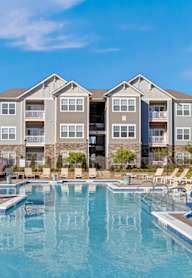 A large swimming pool in front of a multi-story apartment building.