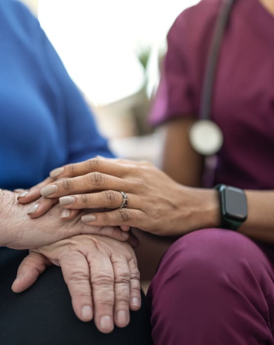 A healthcare worker holds the hand of an elderly patient.