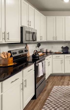 A modern kitchen with white cabinets and black countertops.