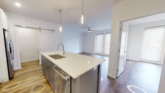 A modern kitchen with white appliances and wooden flooring.