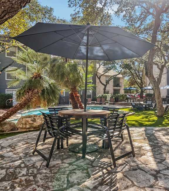 A patio with a table and chairs under an umbrella.