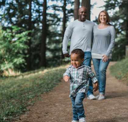 Man, woman, and child walking on a trail in a forest