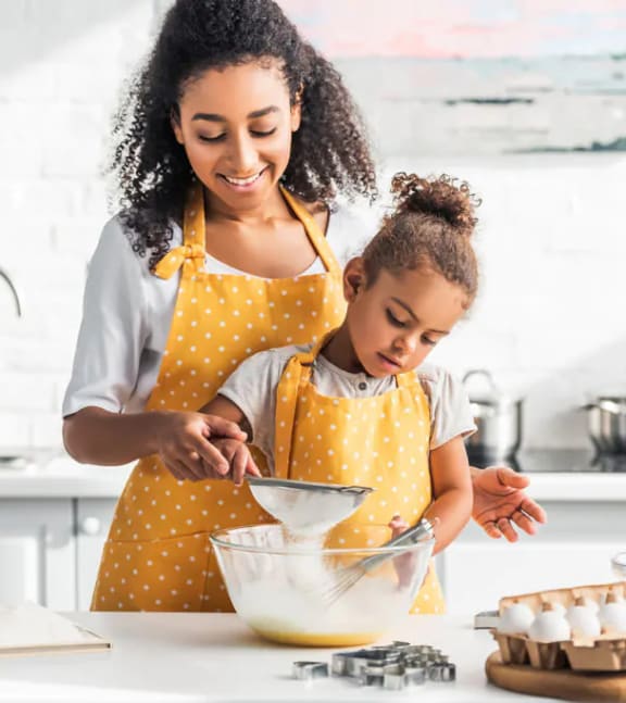 a mother and daughter preparing food in the kitchen