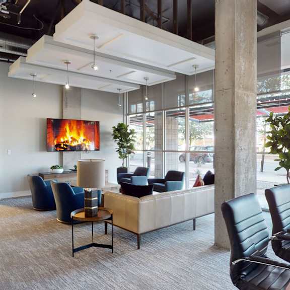 The lounge at Skyline Lofts with a couch, plush chairs, a television, and a conference table and chairs. 